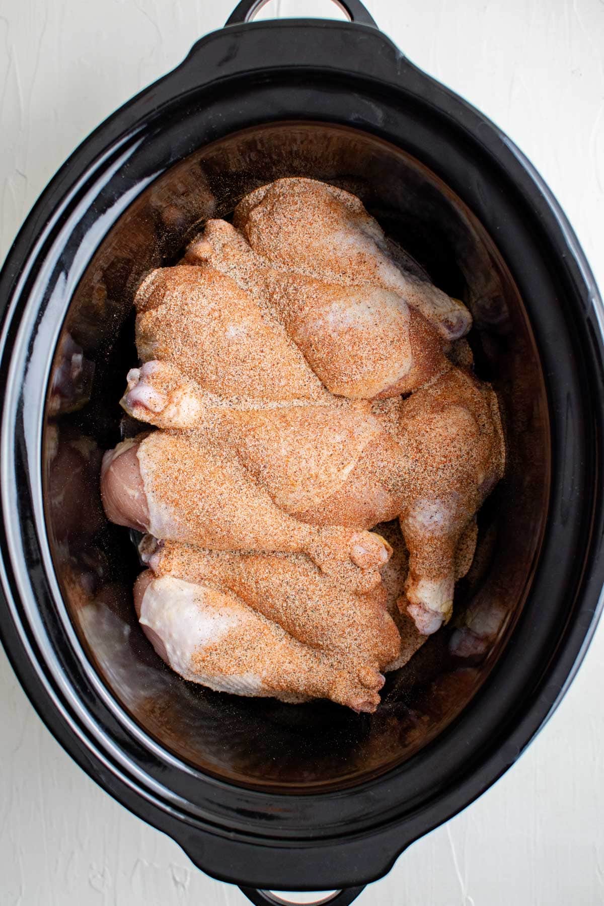 chicken drumsticks in a slow cooker with seasoning
