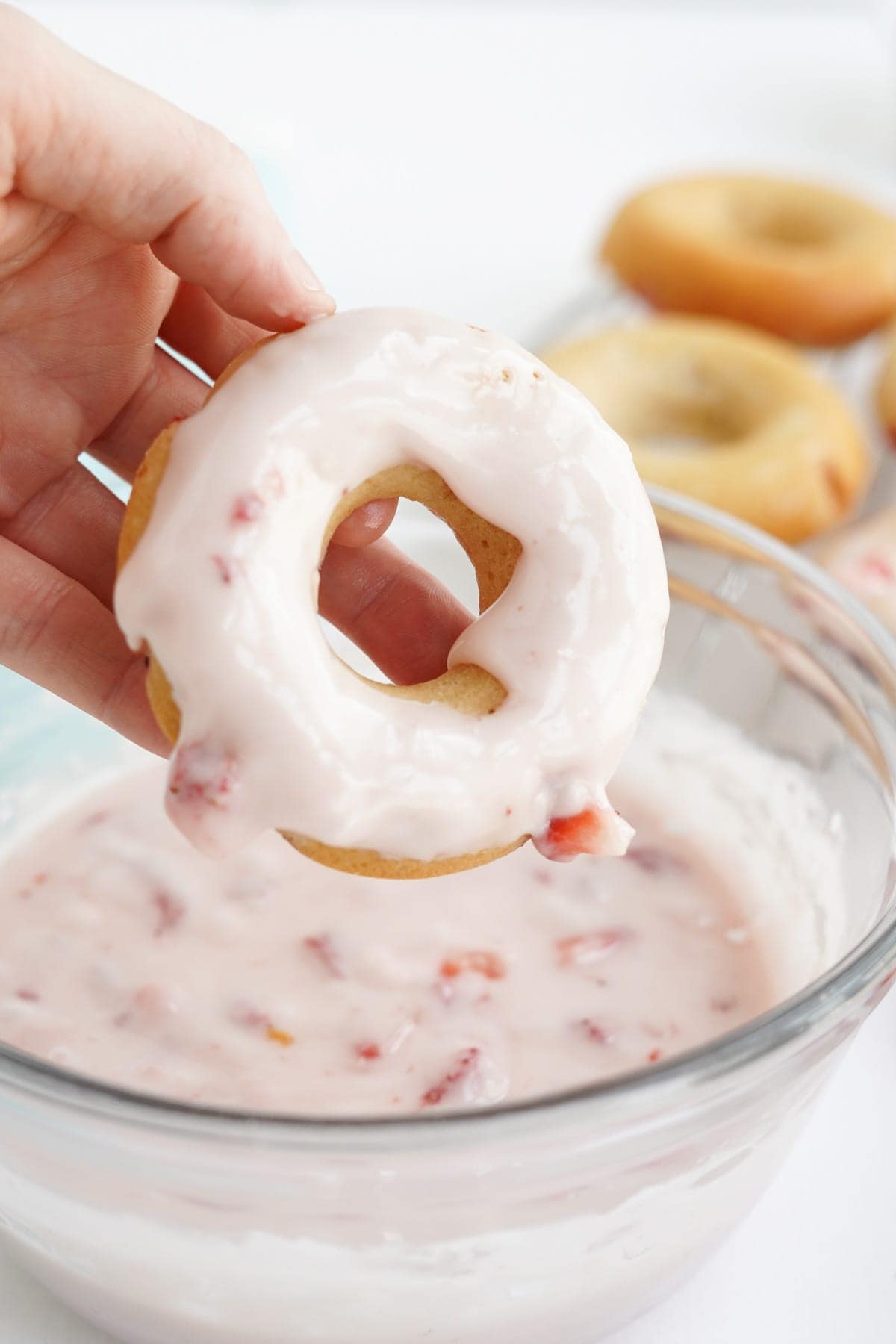 hand holding a doughnut after dipping in glaze