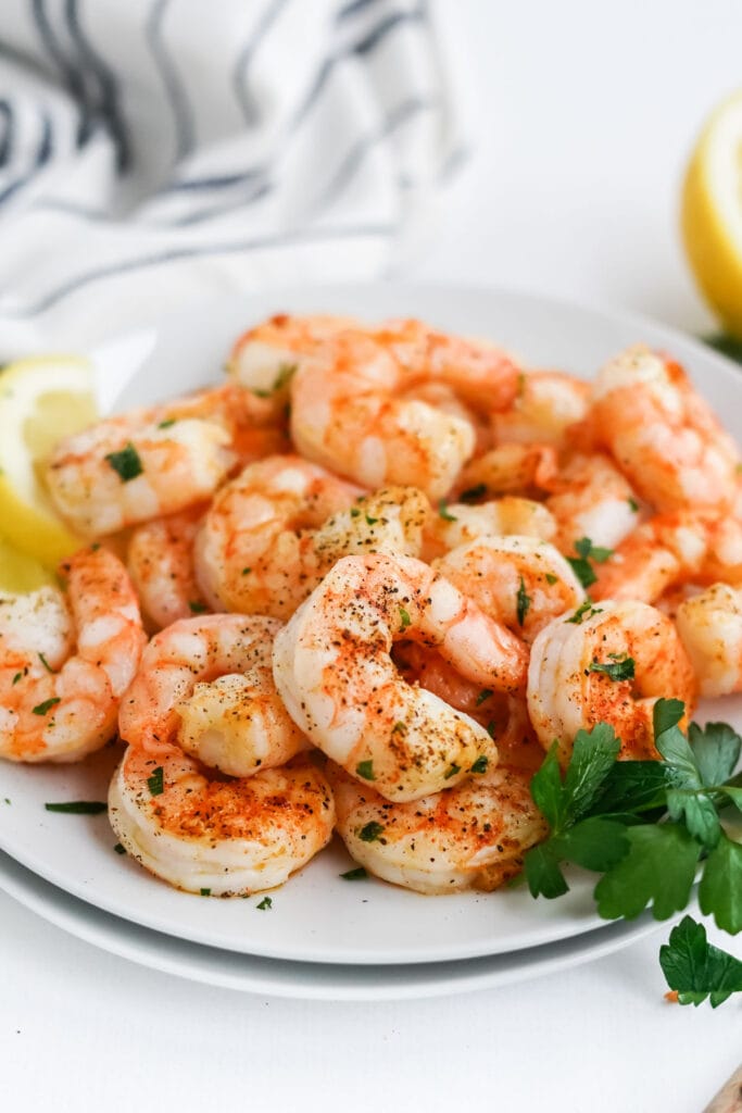 air fryer shrimp on a white plate with parsley and lemon