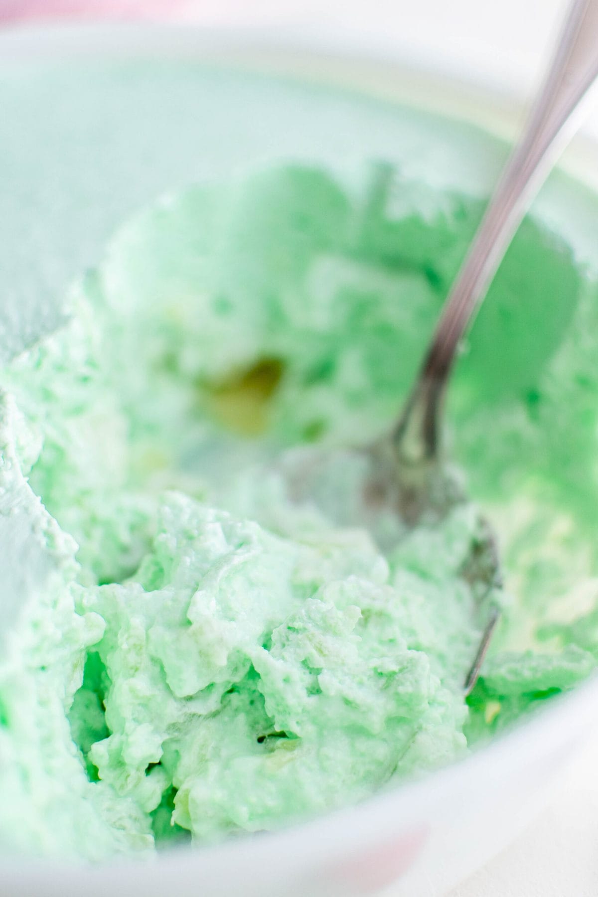 green jello salad in a white dish with a spoon
