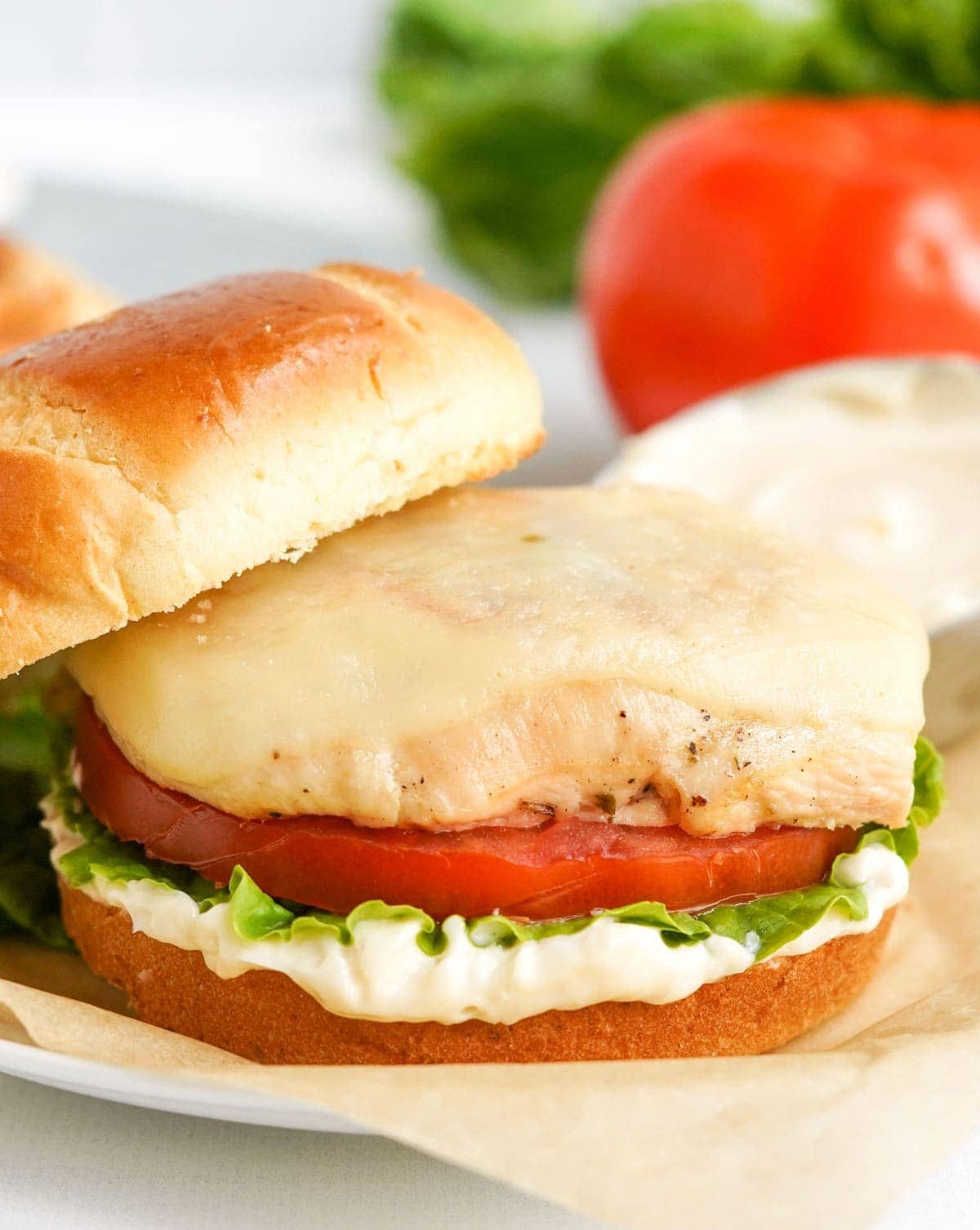 grilled chicken, tomato, lettuce, may on a brioche bun with the top half slightly off