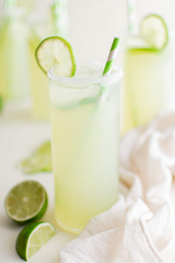 glass of limeade with limes