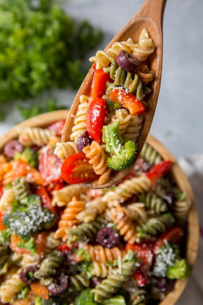 pasta, vegetables in a wood bowl with a wood spoon