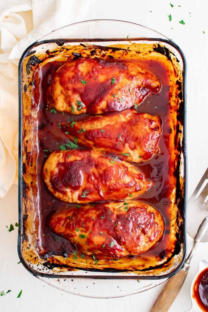 baking dish with 4 pieces of chicken breast covered in bbq sauce