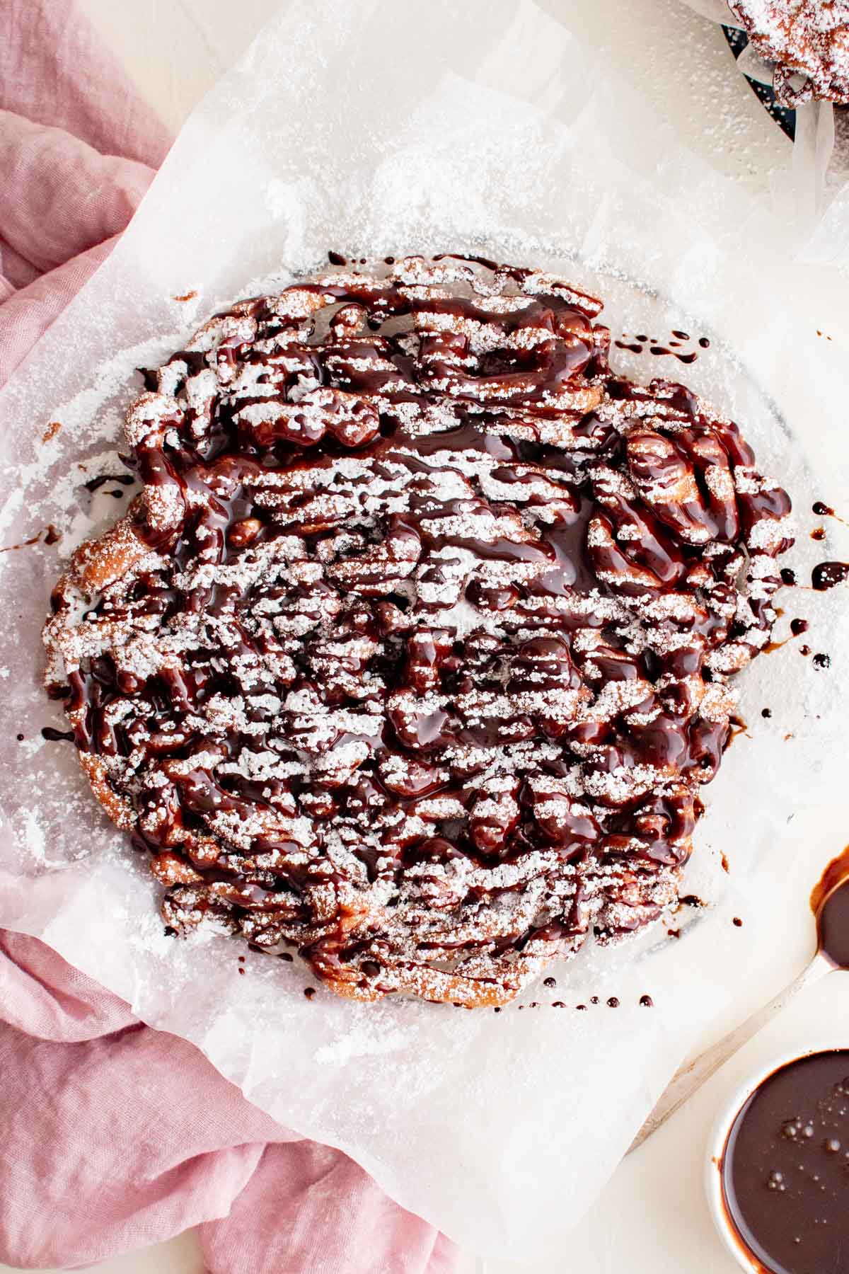 chocolate sauce and powdered sugar on a cricpy funnel cake