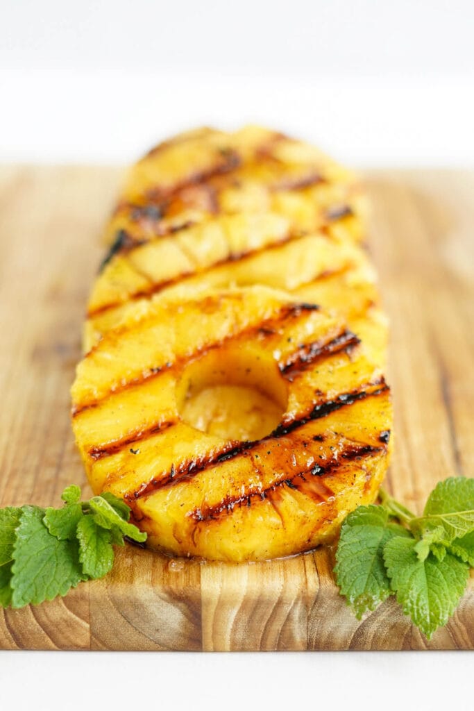 pineapple slices with grill marks on a cutting board