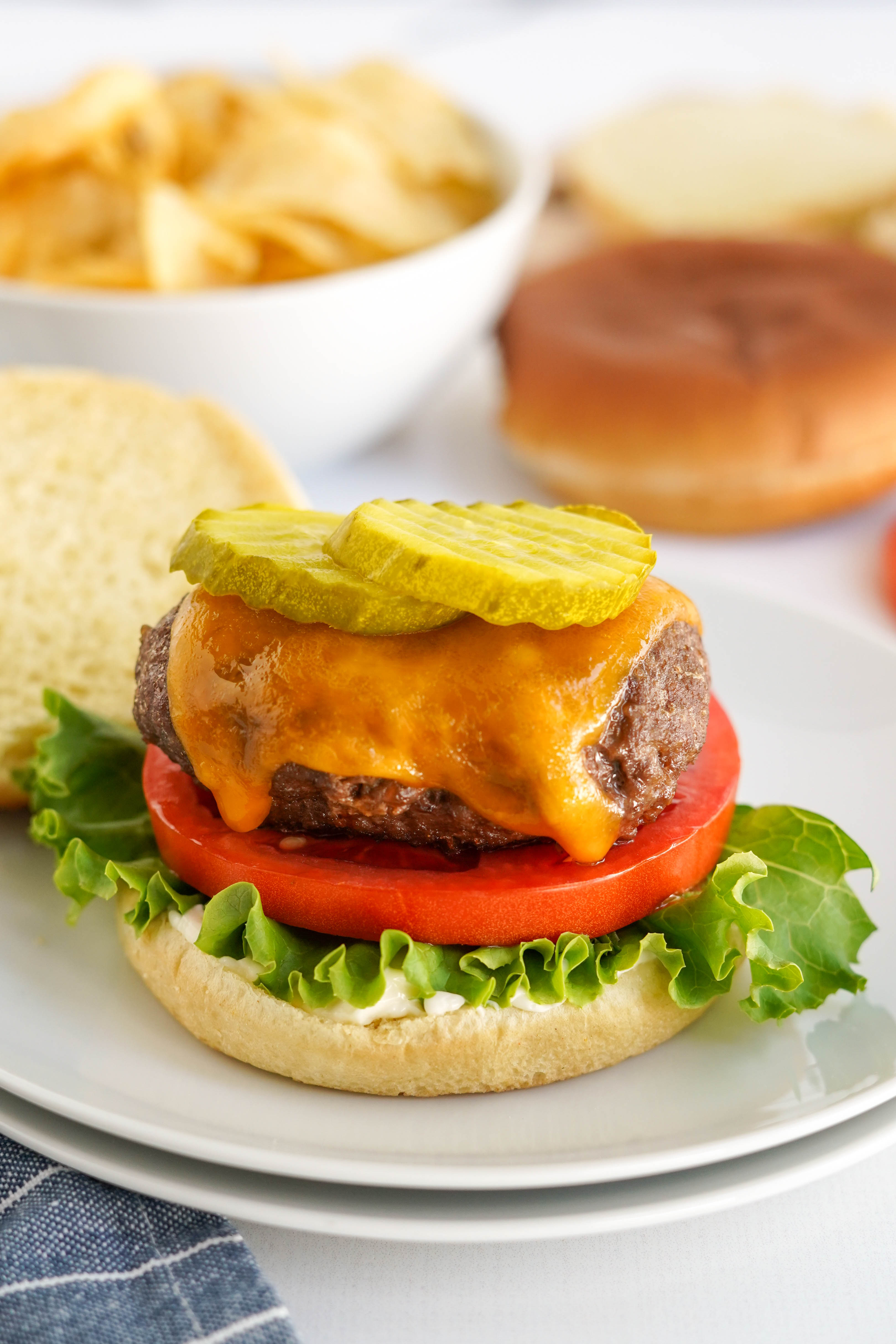 hamburger patty on buns with lettuce, tomatoes and pickles