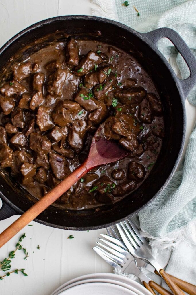 gravy and beef in a skillet with wooden spoon