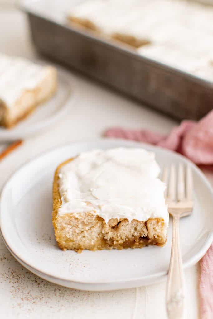 cinnamon roll cake on a white plate with a fork 