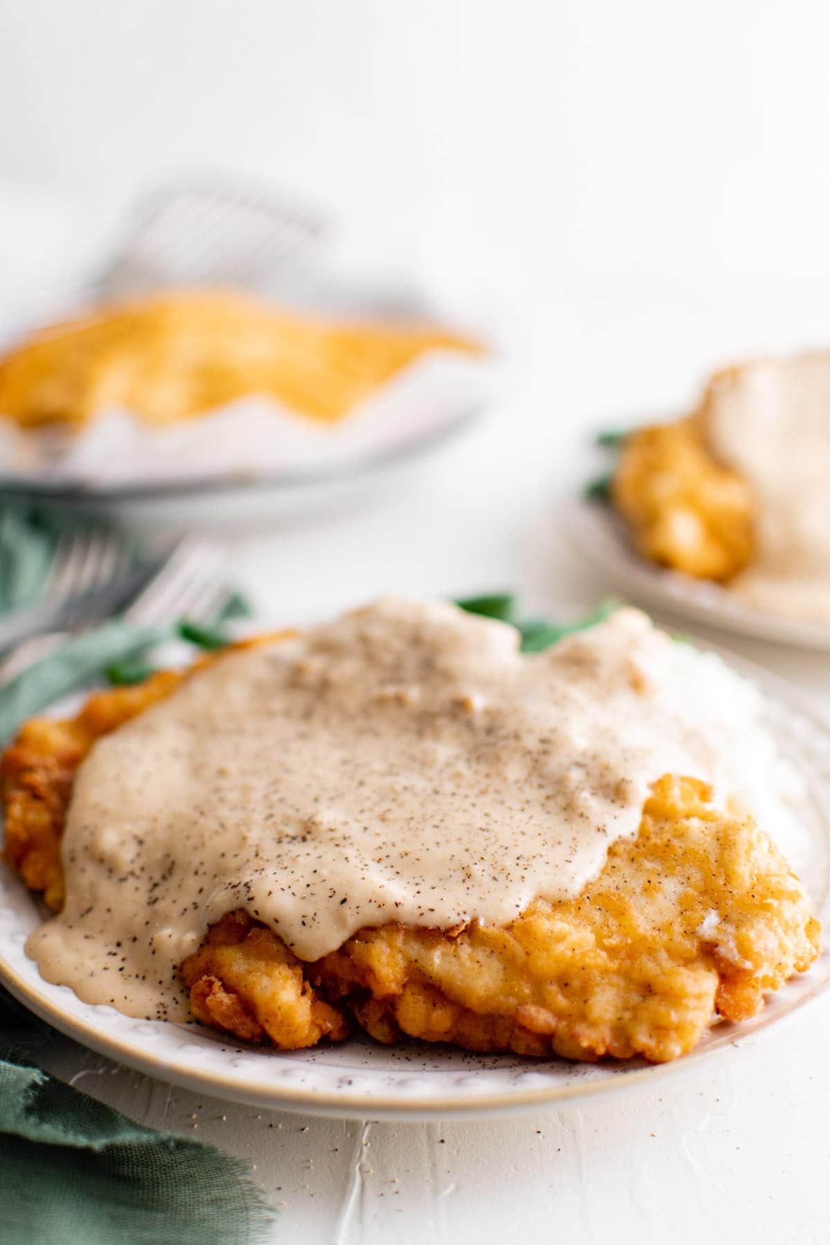 chicken fried chicken with gravy on a plate with green beans and mashed potatoes