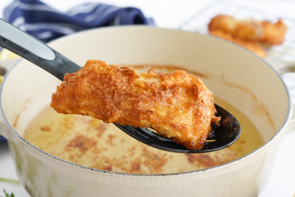 piece of fried fish on a slotted spoon
