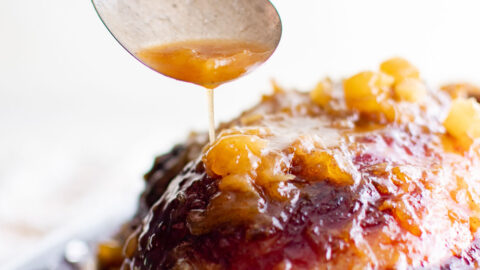 spooning juices over a ham