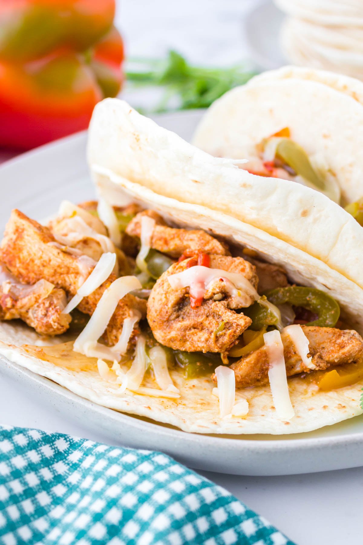 chicken and bell peppers in flour tortilla on a white plate