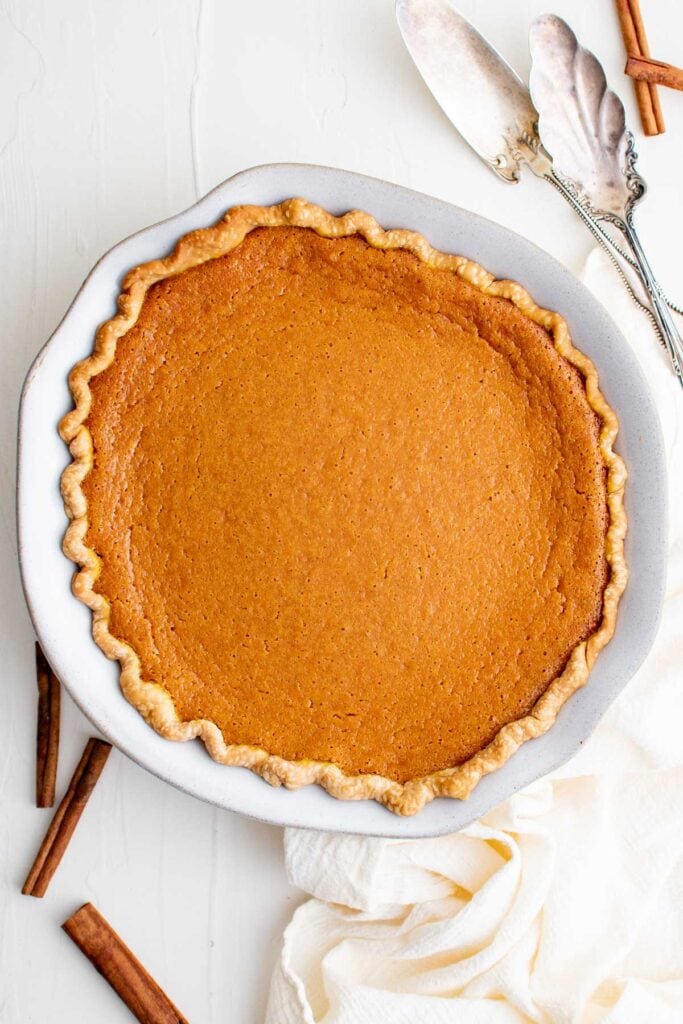 sweet potato pie in a pie dish, cinnamon sticks