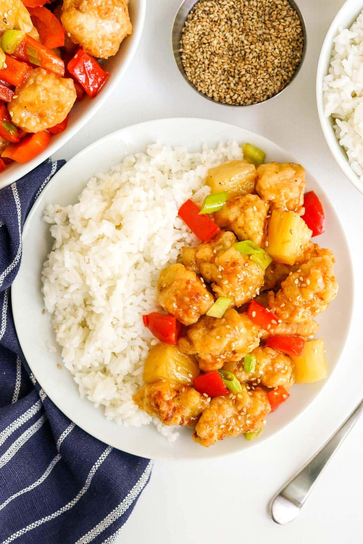 white rice and sweet and sour chicken with vegetables on a plate