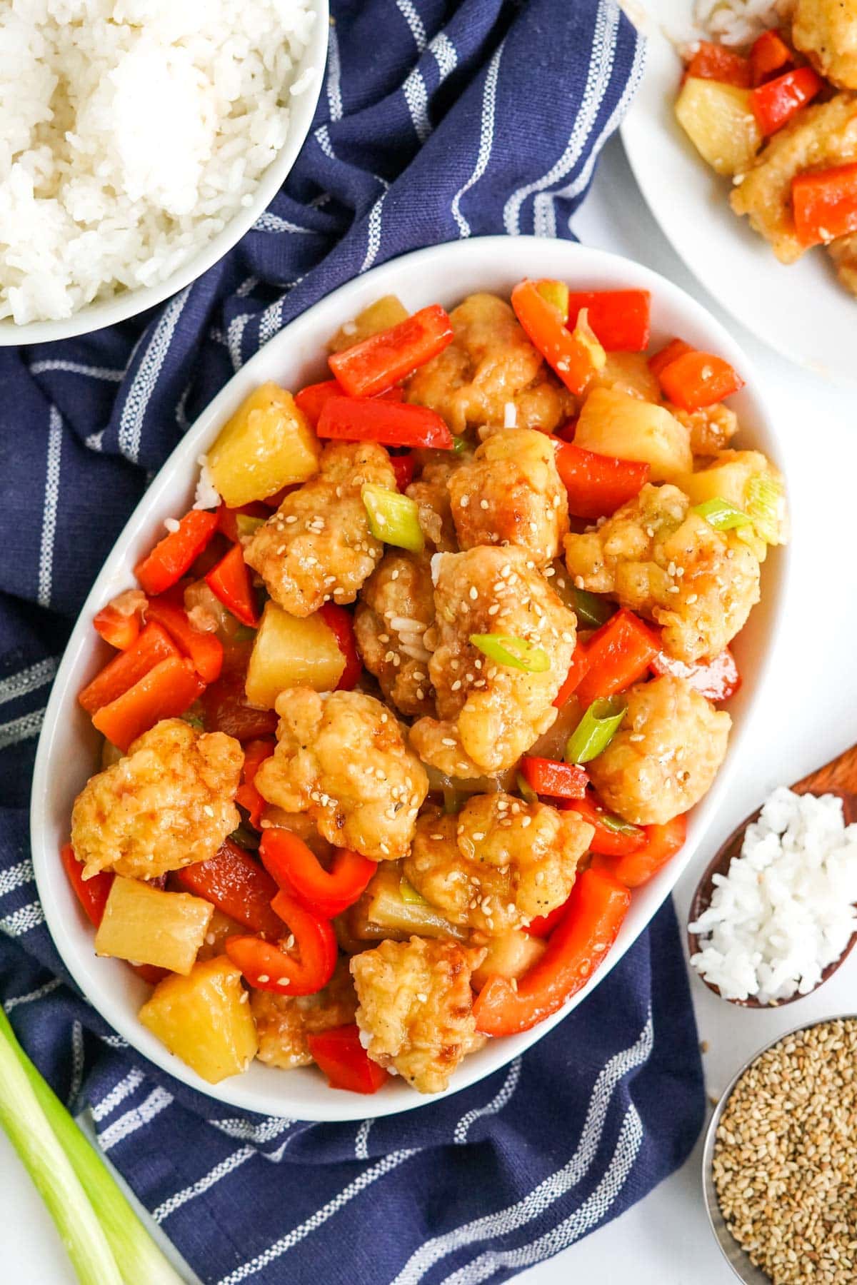 sweet and sour chicken with bell peppers and pineapple on a white platter