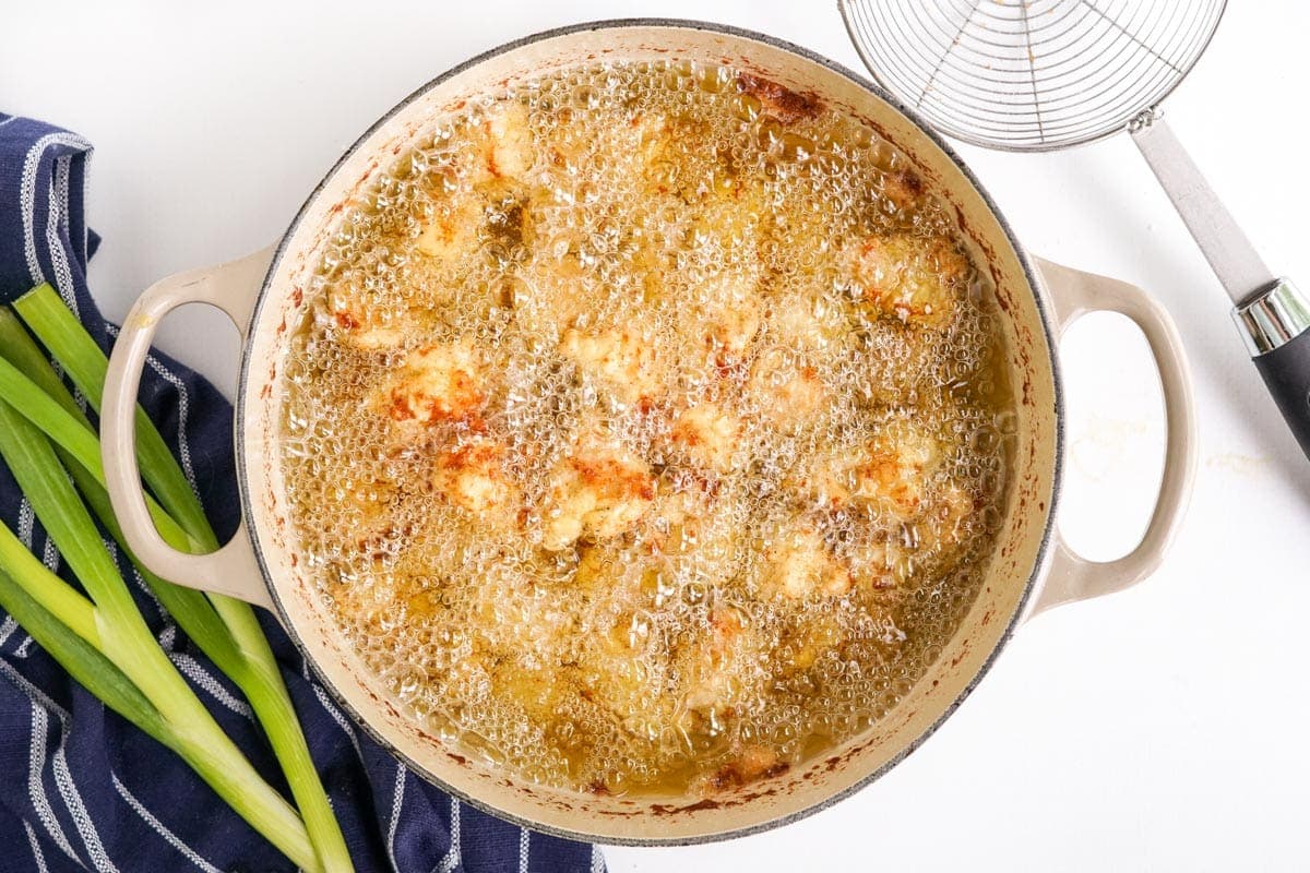 breaded chicken frying in a pot of oil