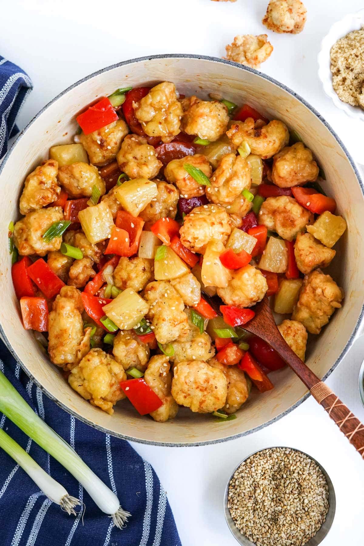 bread chicken pieces and veggies in a pot with sweet and sour sauce