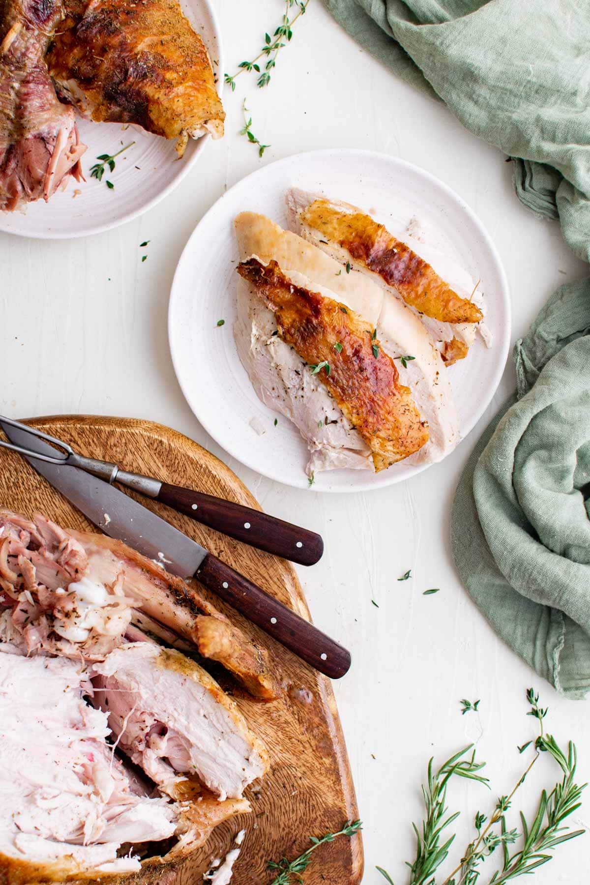 sliced turkey breast on a white plate, turkey on a cutting board