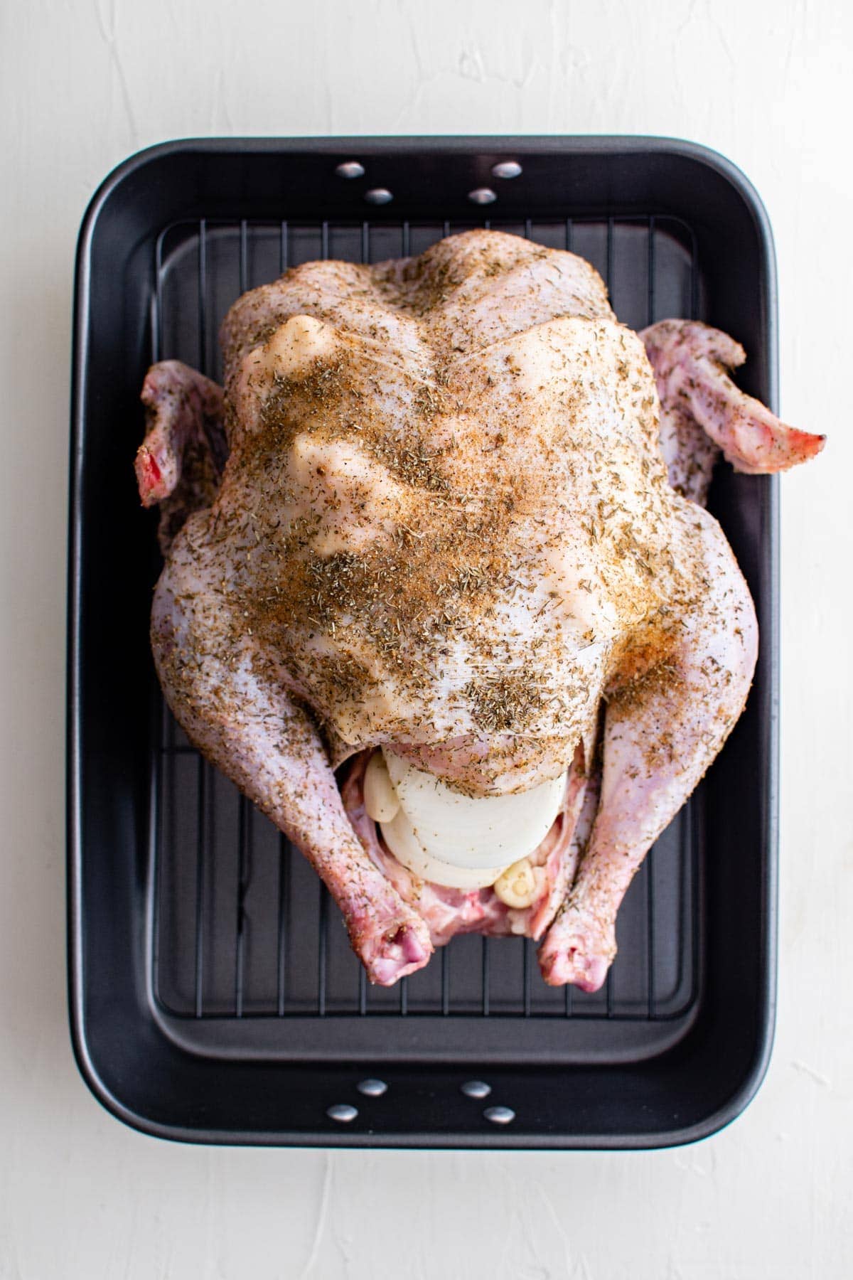 whole raw turkey on a roasting rack in a pan