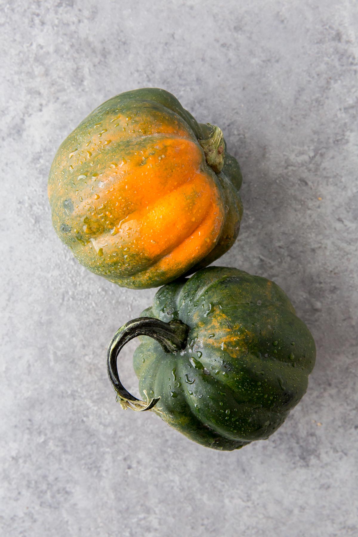 2 whole acorn squash on a gray background