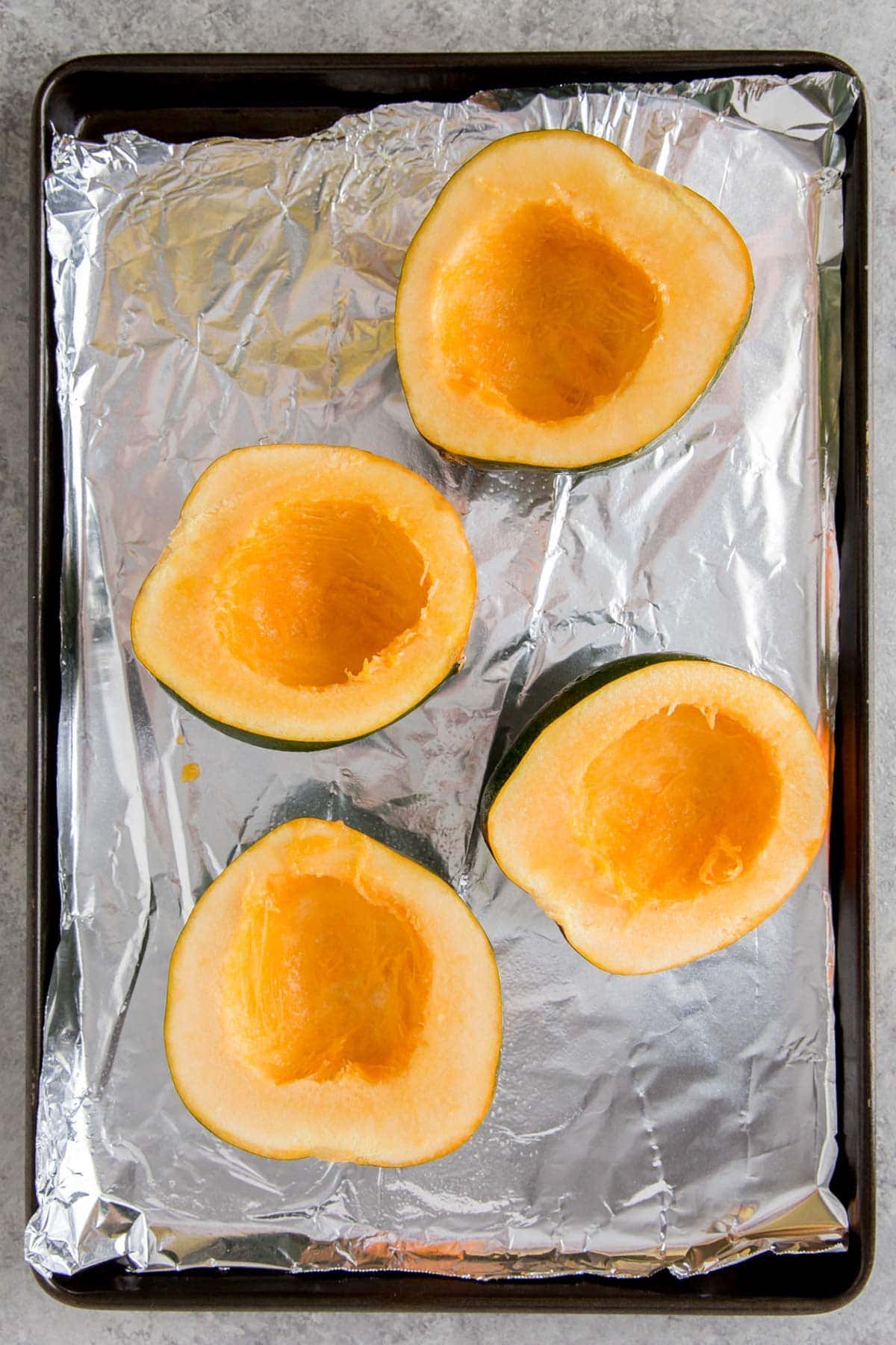 acorn squash, cut side up, on a foil lined baking sheet