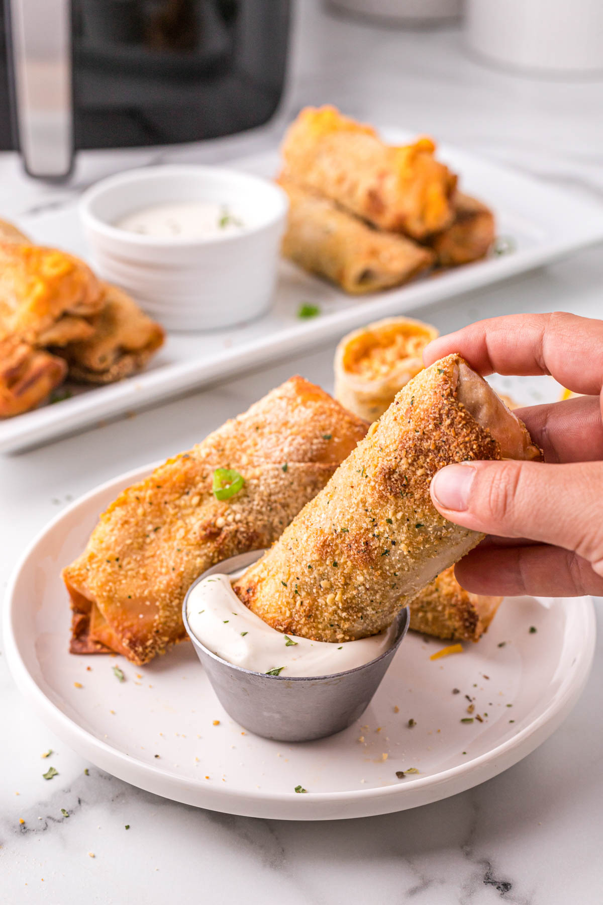 hand holding a buffalo chicken egg roll dipped in ranch