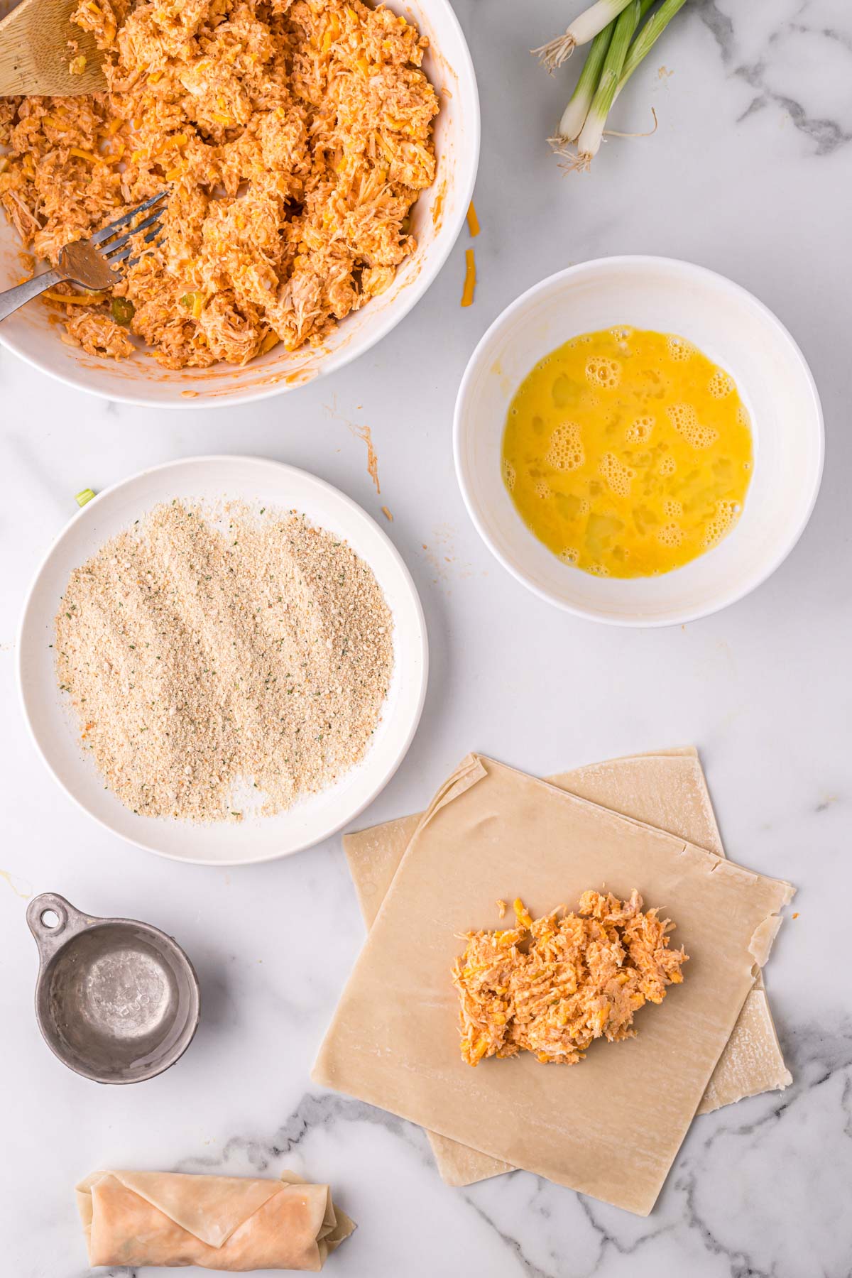 buffalo chicken, dishes of breadcrumbs, egg and egg roll wrappes