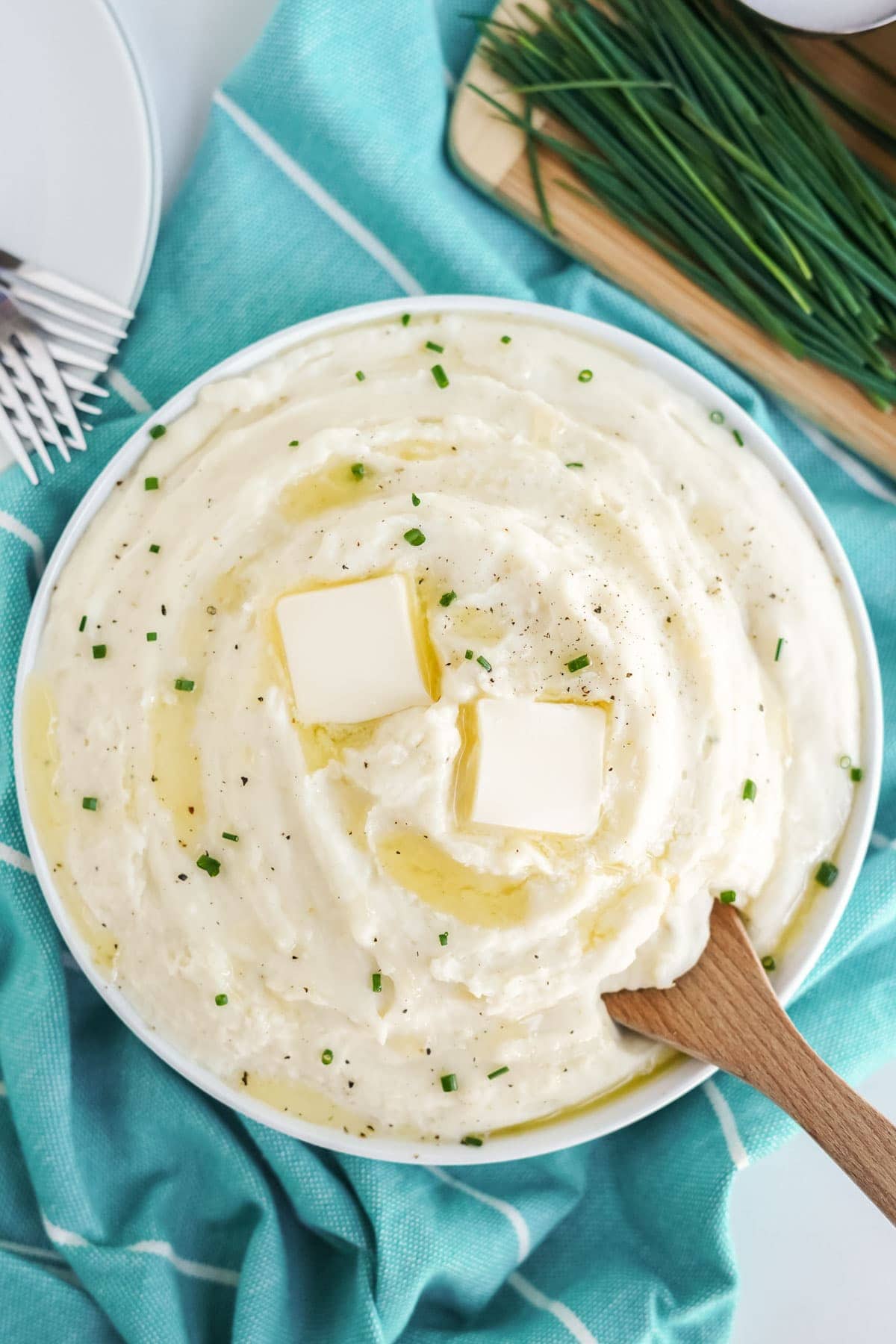 cream cheese mashed potatoes in a white bowl with a wooden spoon.