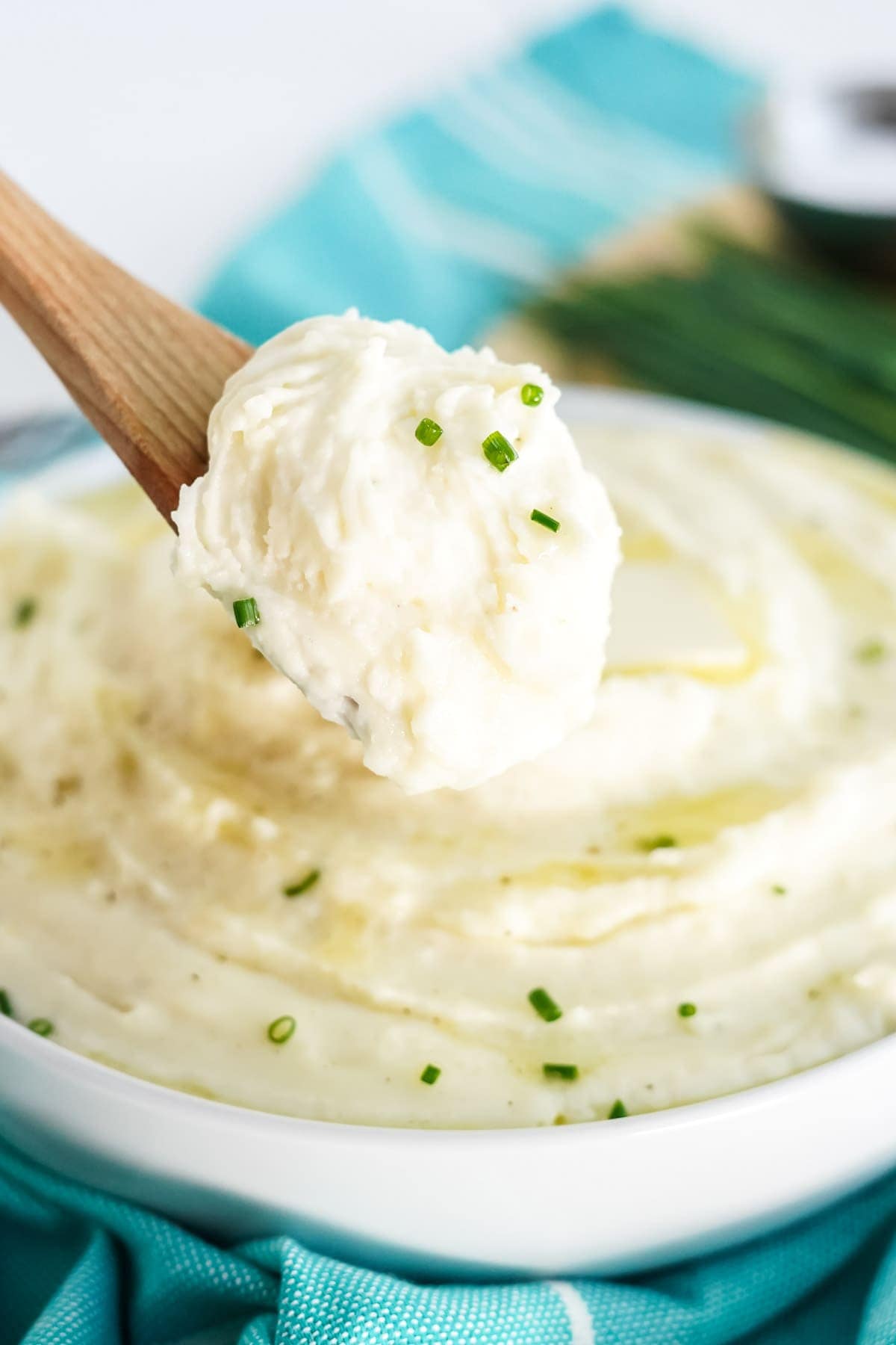cream cheese mashed potatoes on a white plate with a scoop on a wooden spoon