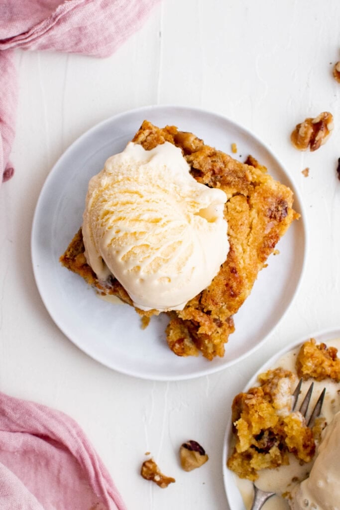 pu mpkin dump cake slice on a white plate with cake and vanilla ice cream