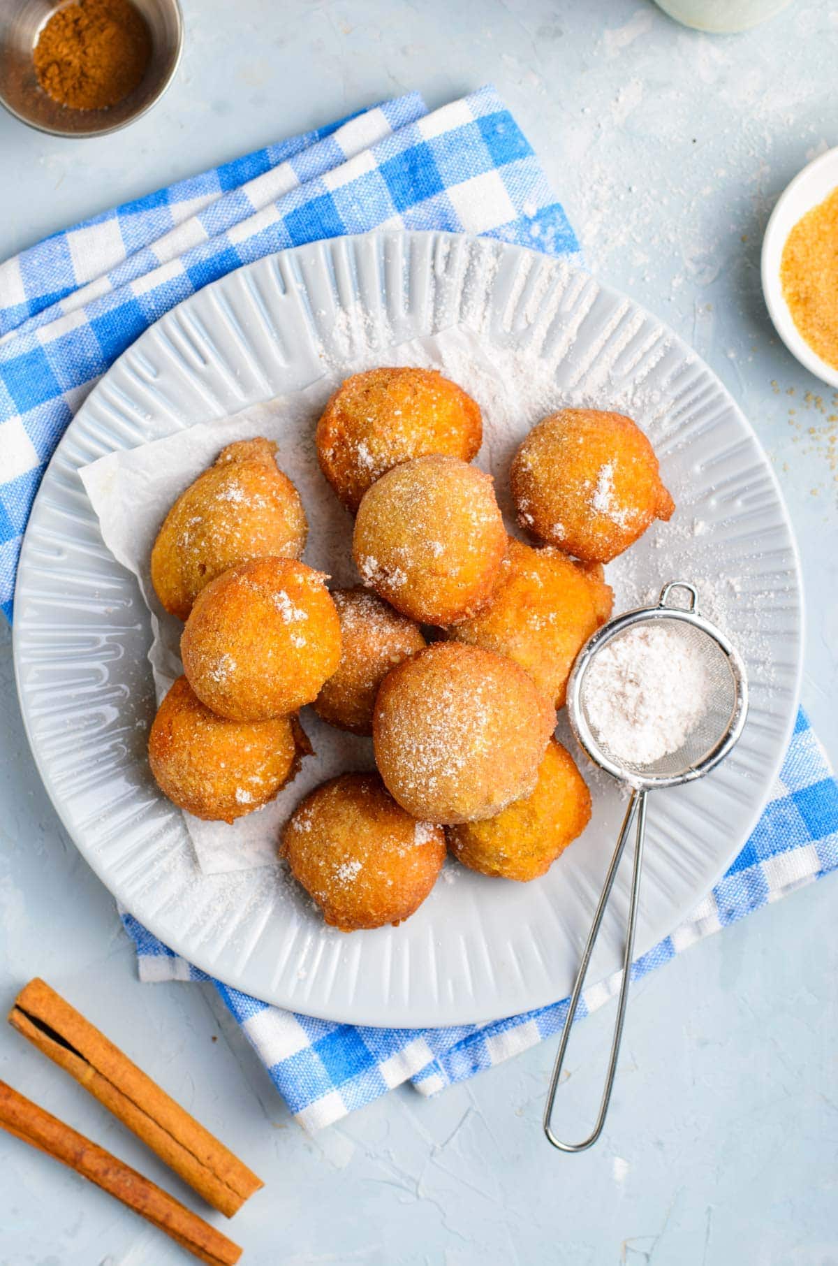 pumpkin fritters, white plate, powdered sugar, cinnamon sticks