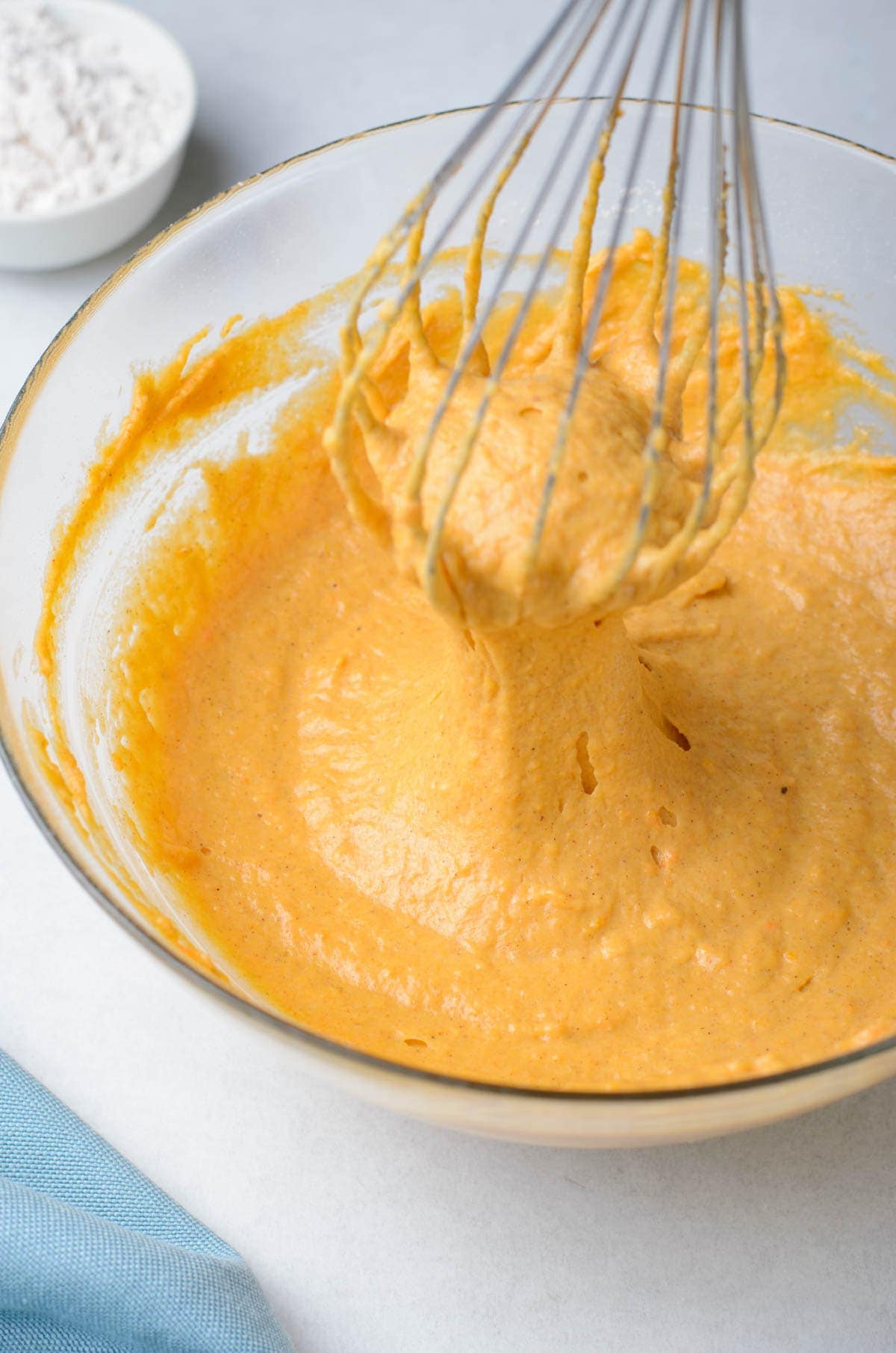 pumpkin fritter batter in clear glass bowl, whisk