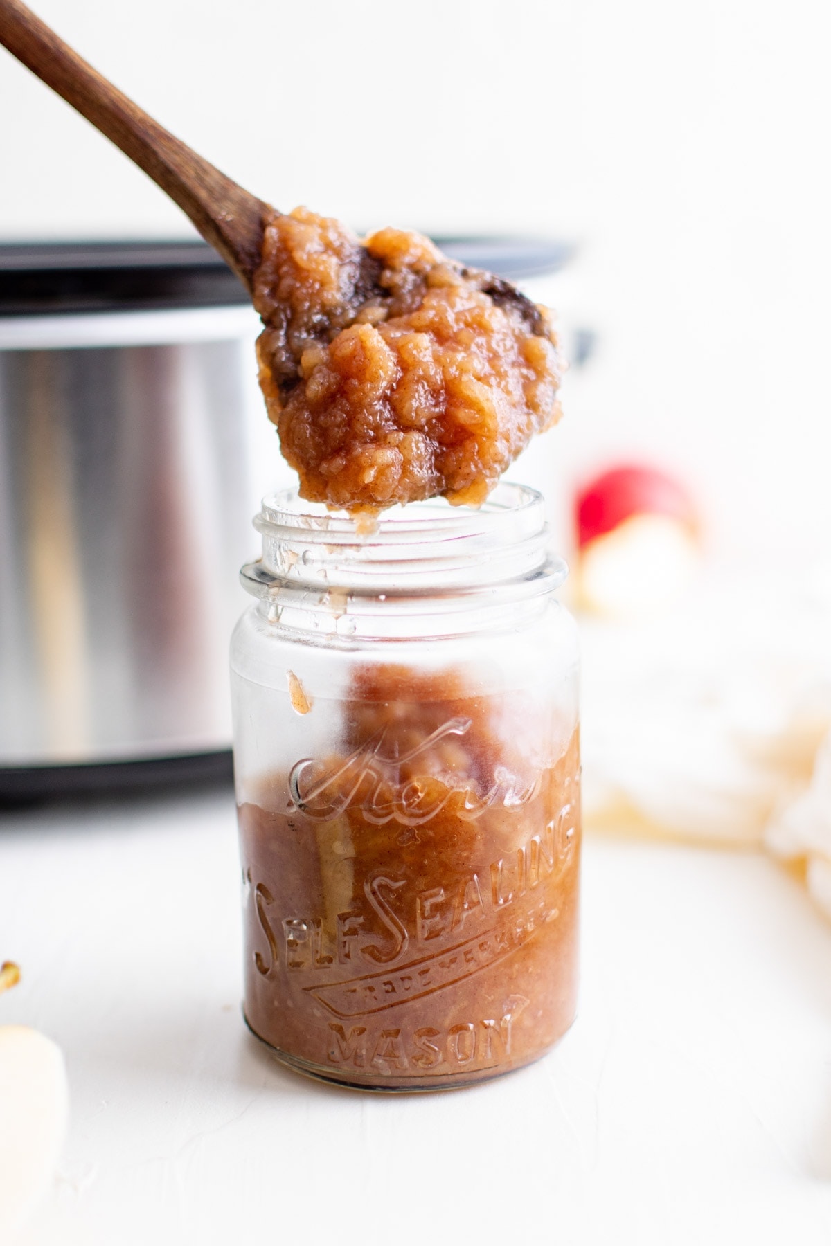 wooden spoon pouring applesauce into jar