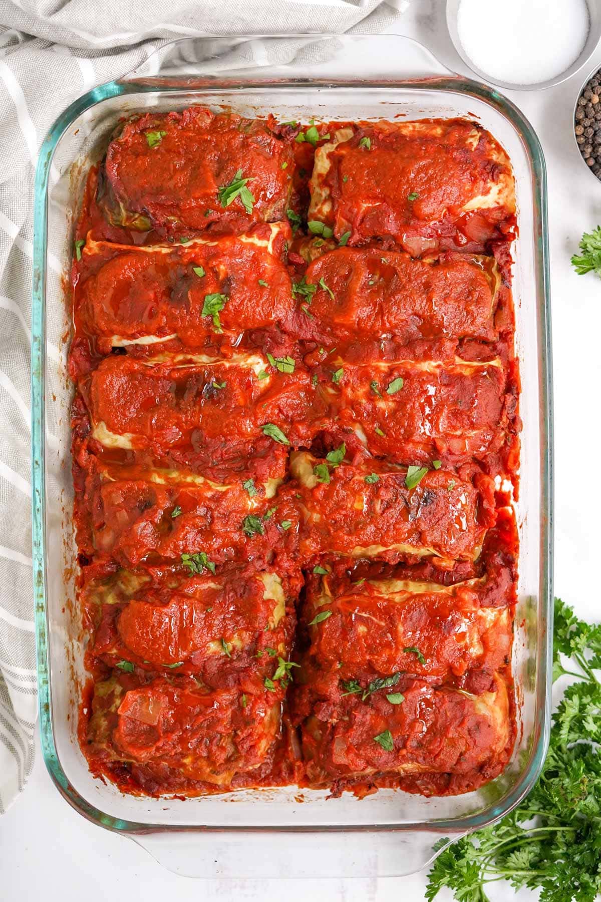 clear glass baking dish with cabbage rolls and sauce