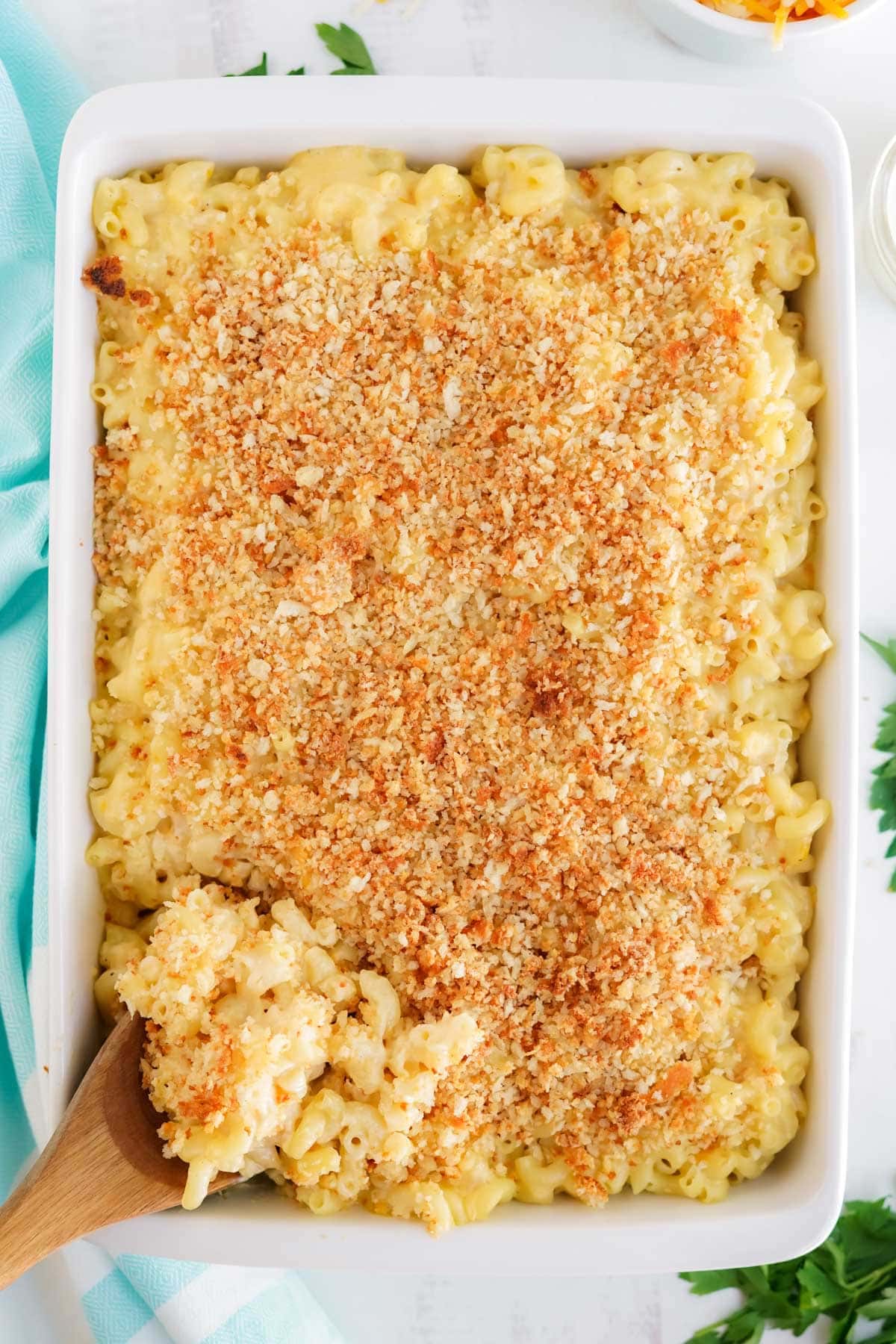 crab mac and cheese in a white baking dish with a woodedn spoon
