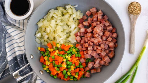 diced onions, ham, peas and carrots in a wok