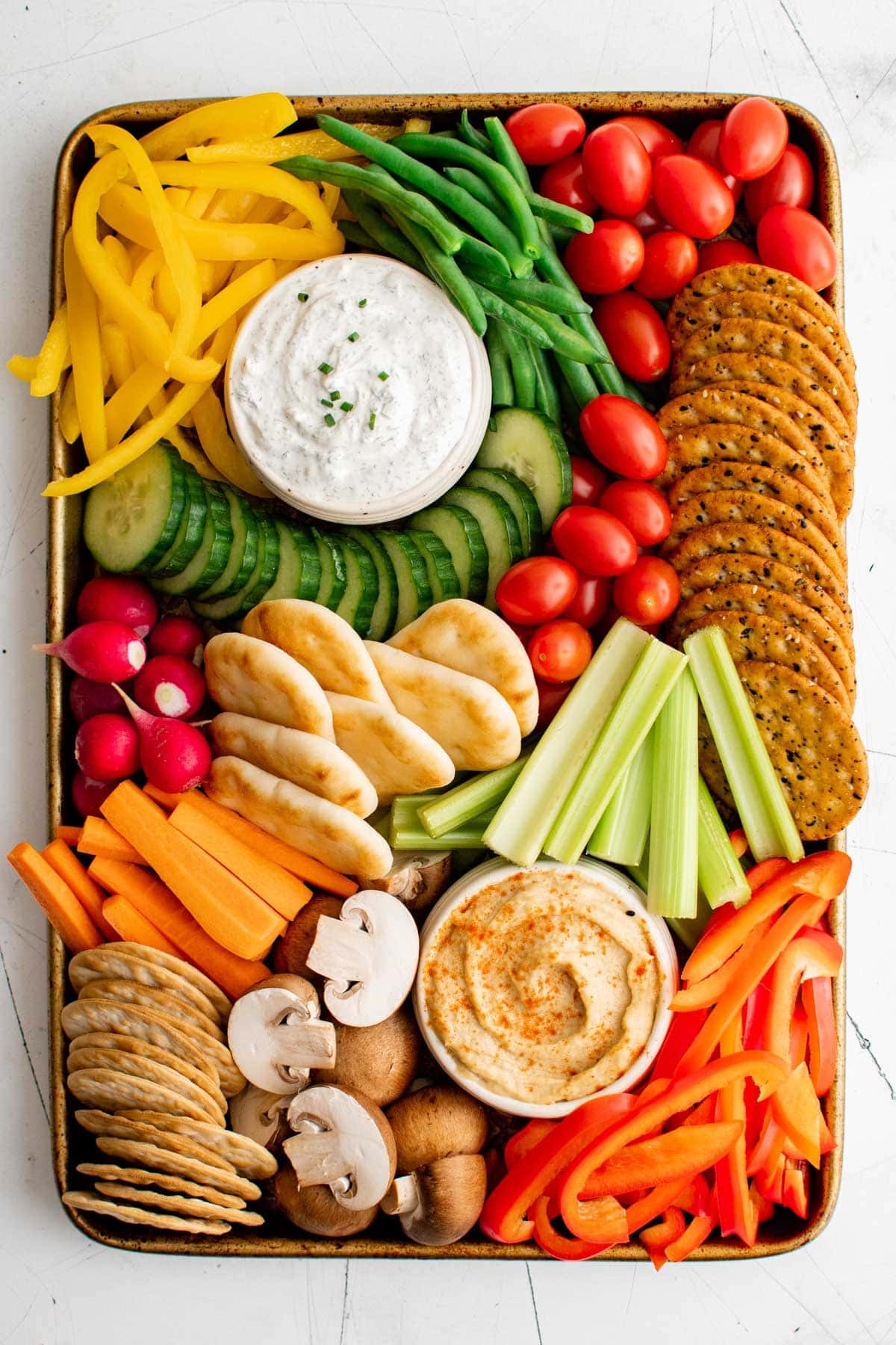 veggie tray with cut up vegetables, bowls of dip and crackers