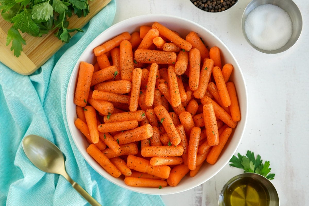 baby carrots in a white dish with parsley