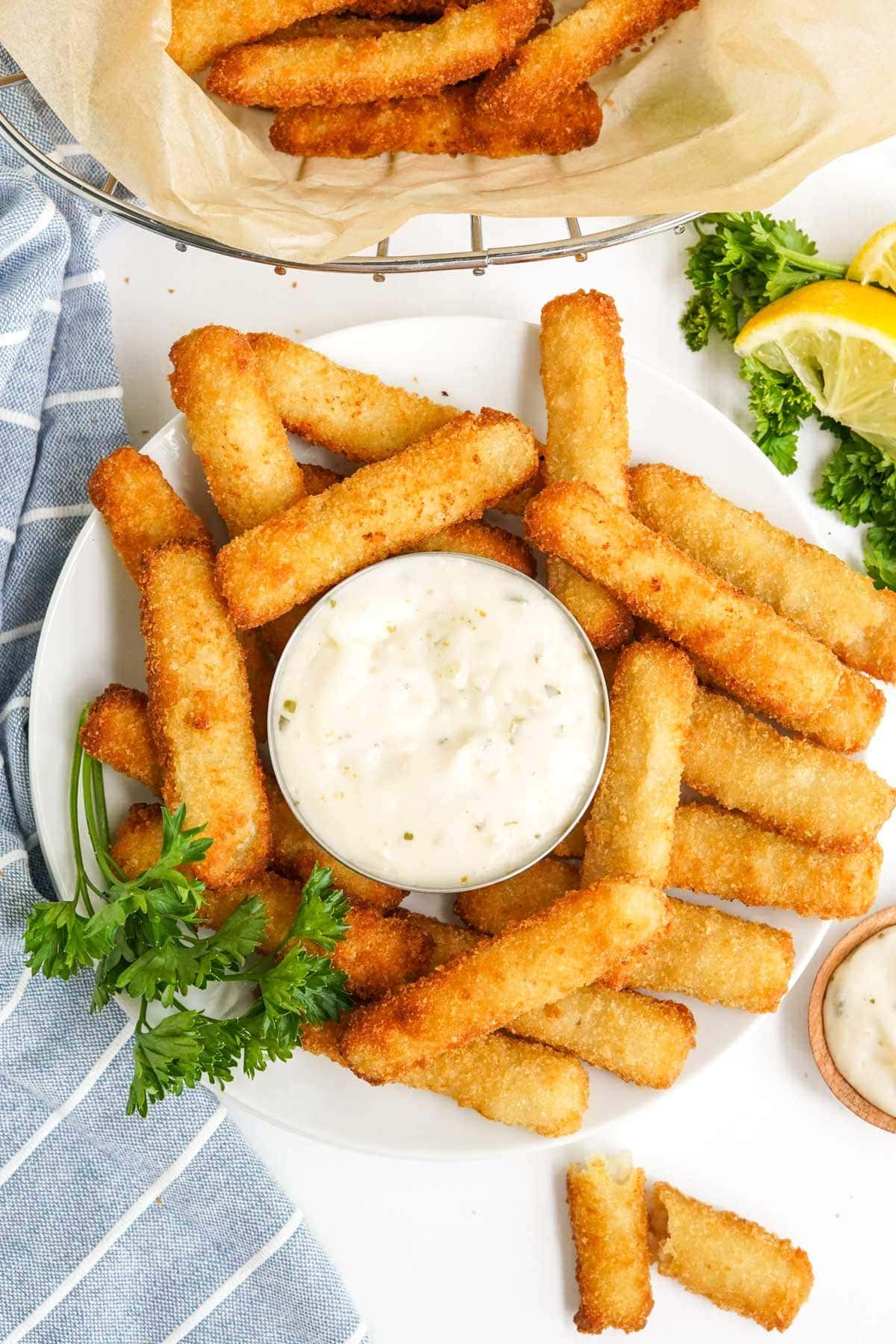 fish stics on a white plate with tartar sauce and lemon