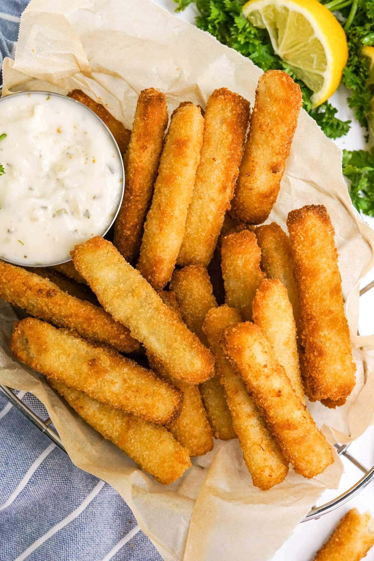 fish sticks serves in a basket with paper and tartar sauce
