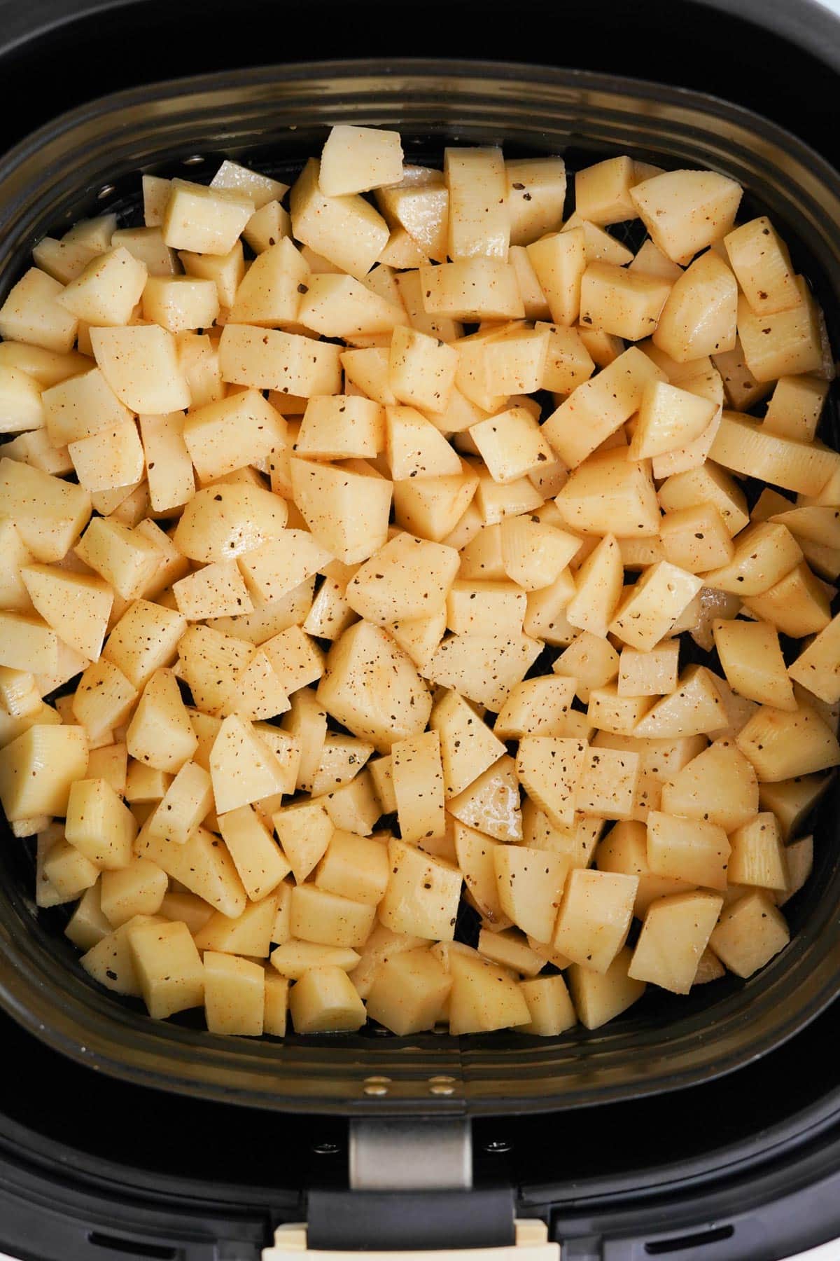 raw cut up potatoes in an air fryer
