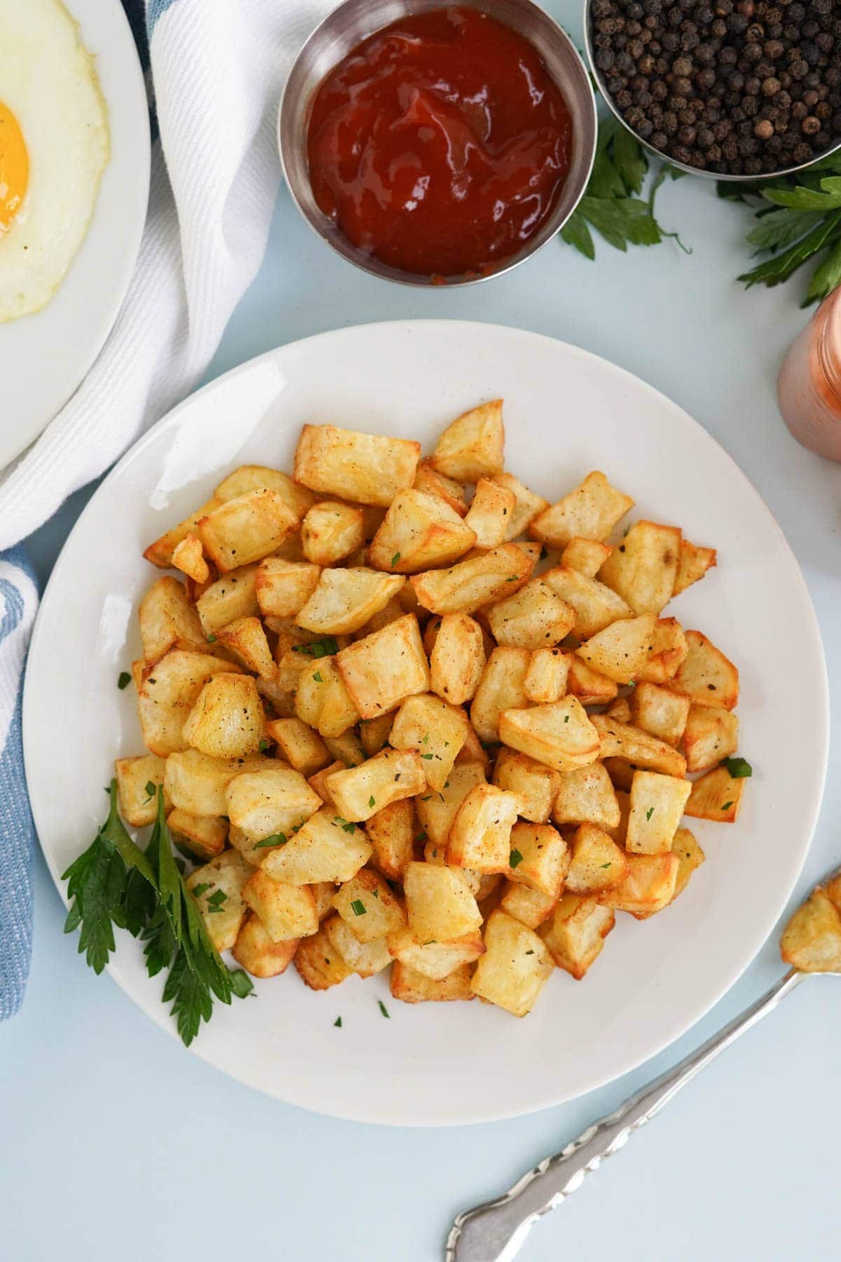 air fryer home fries on a white plate, and a dish of ketchup