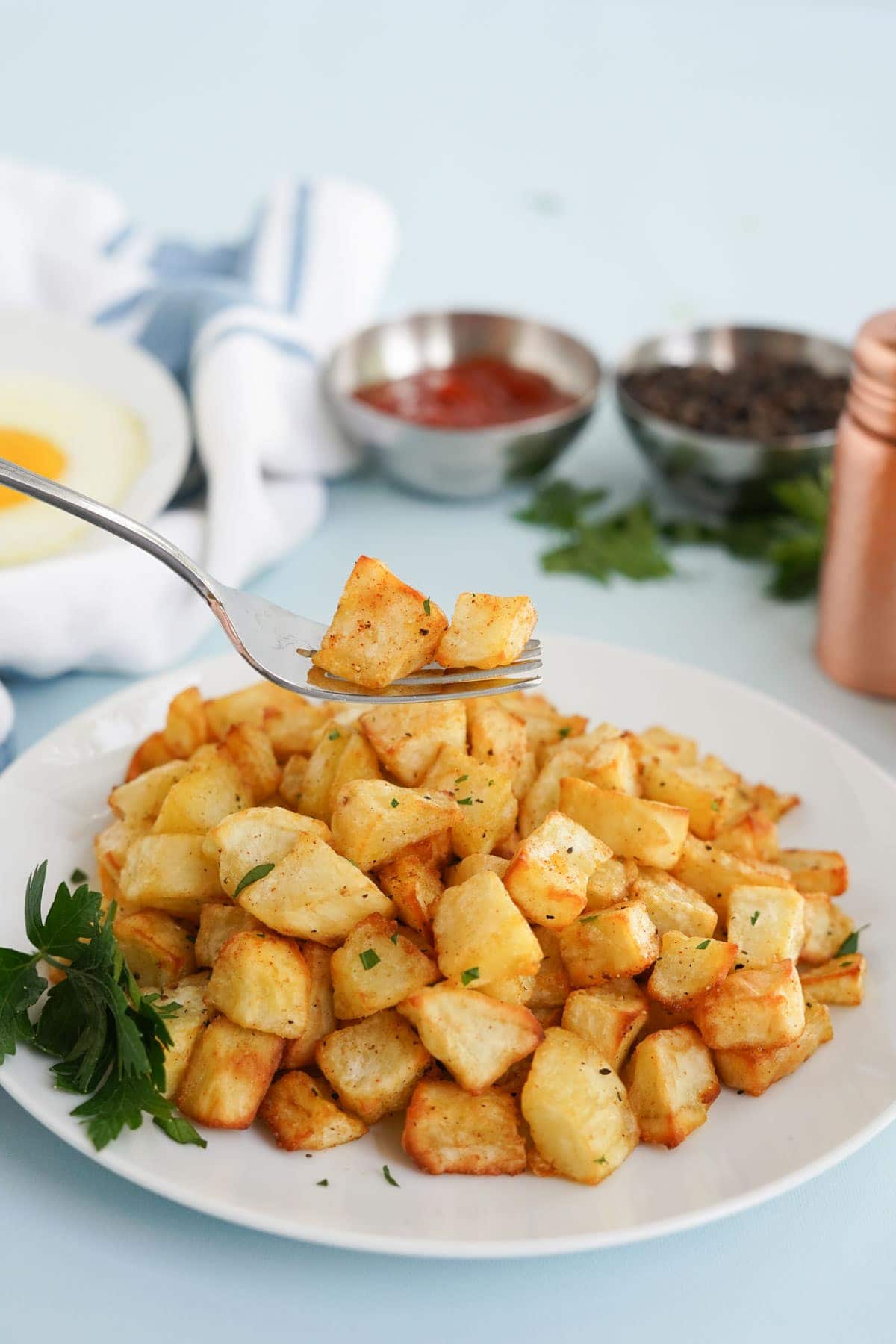 air fryer home fries on a plate,  and a fork