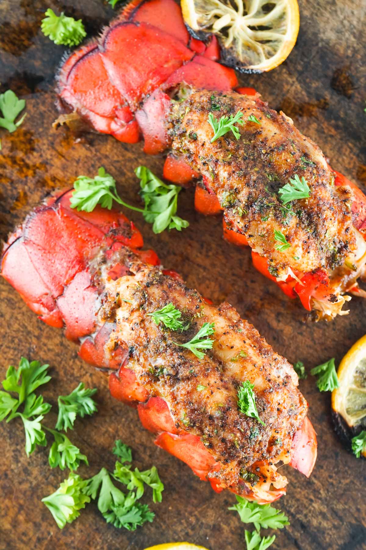 two baked lobster tails with parsley and lemon