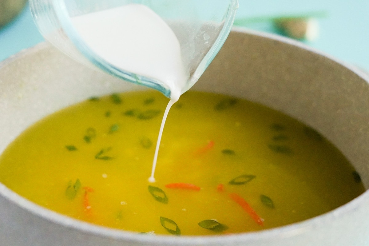 cornstarch slurry being poured into a pot of soup