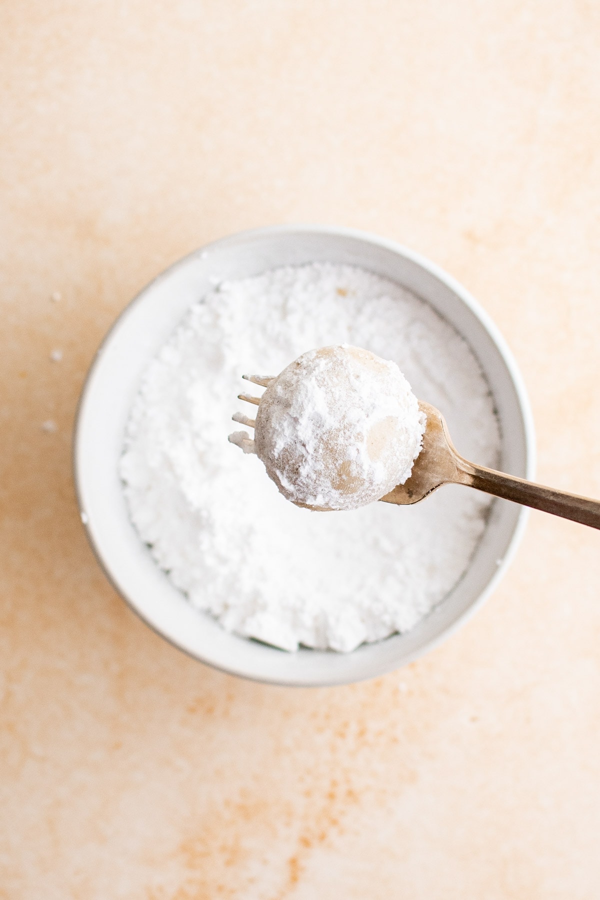 eggnog cookie on a fork over a bowl of powdered sugar