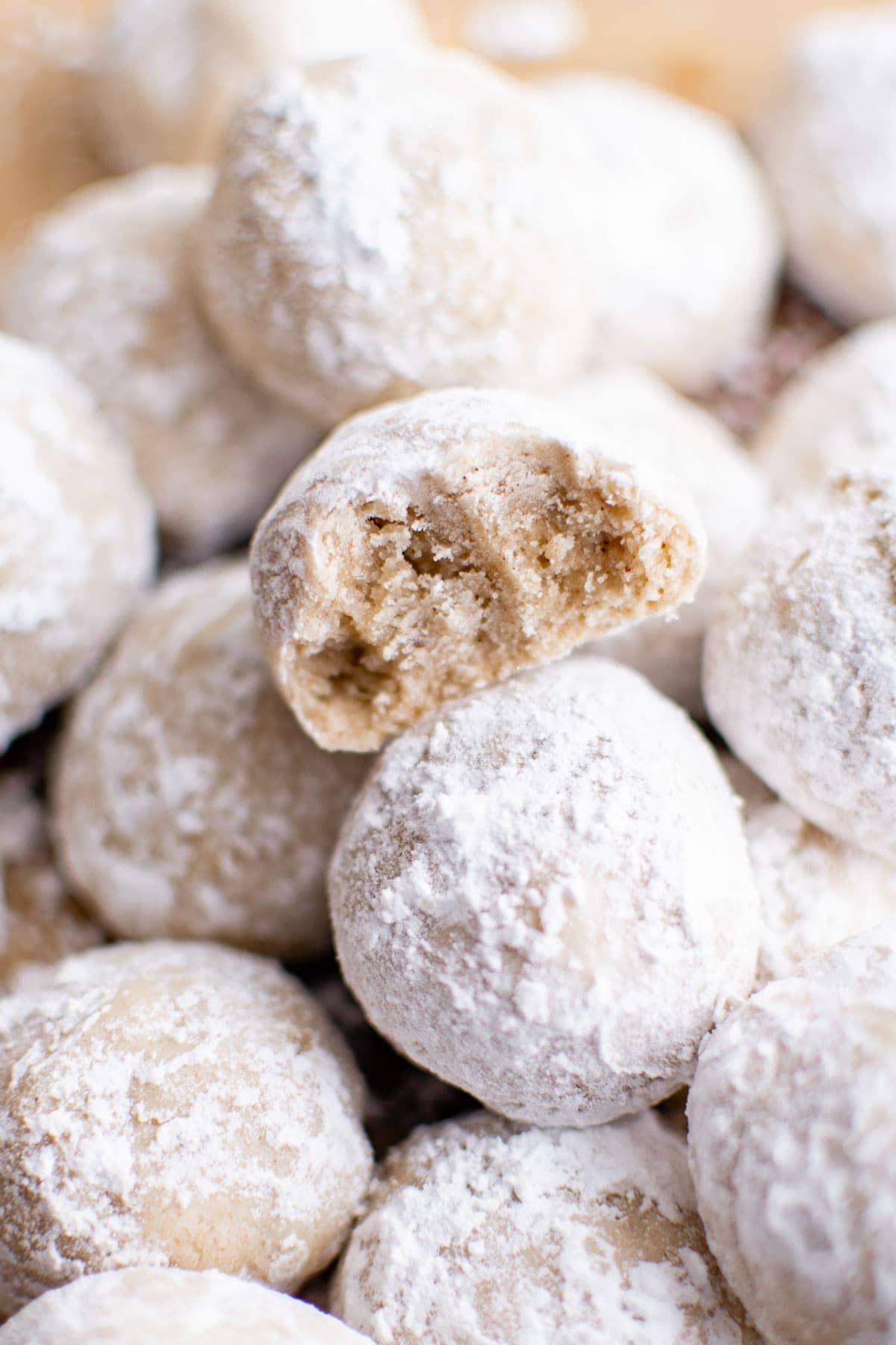 powdered sugar coated eggnog cookies in a pile with a bite taken out of one.