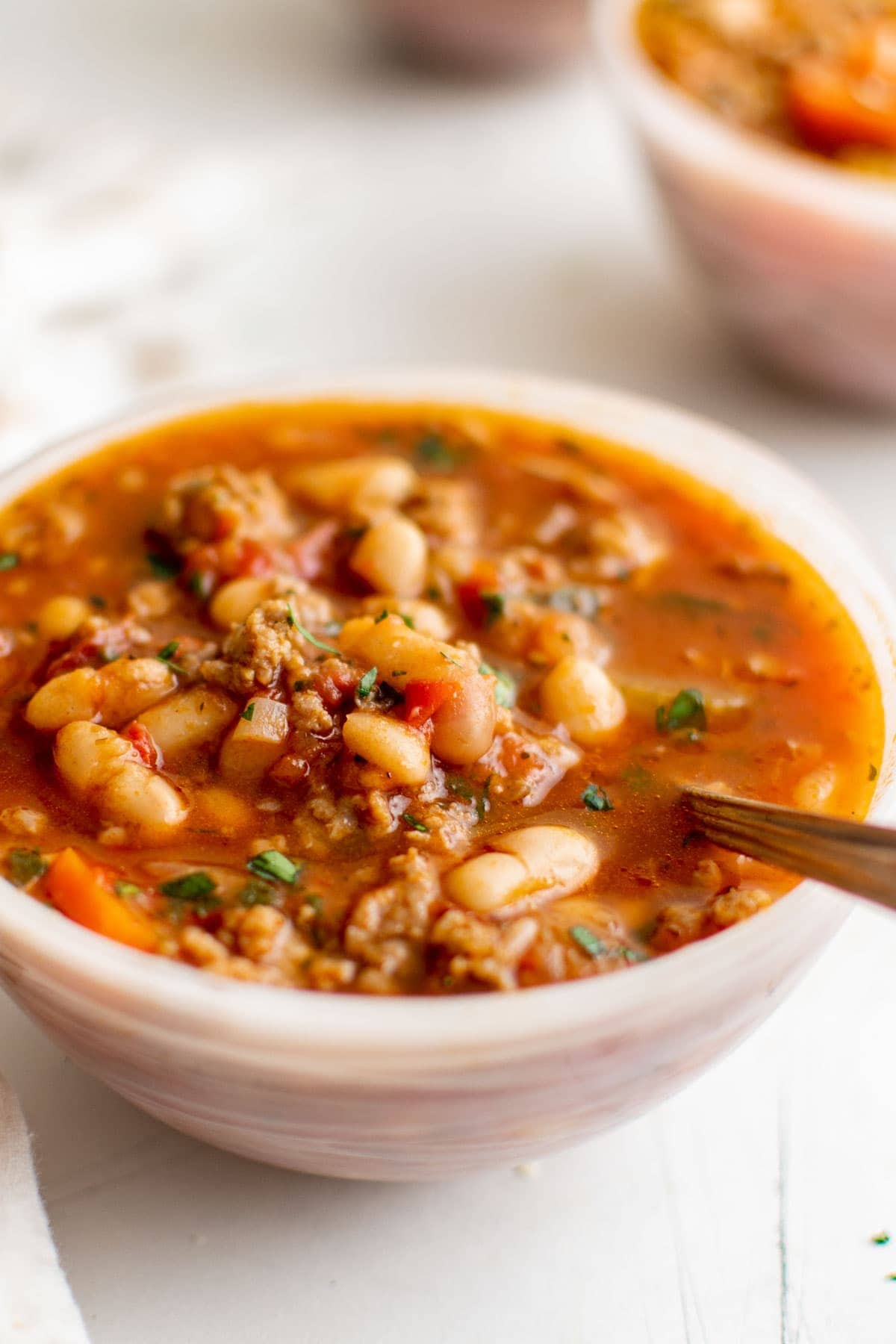 italian bean soup in a white bowl with a spoon