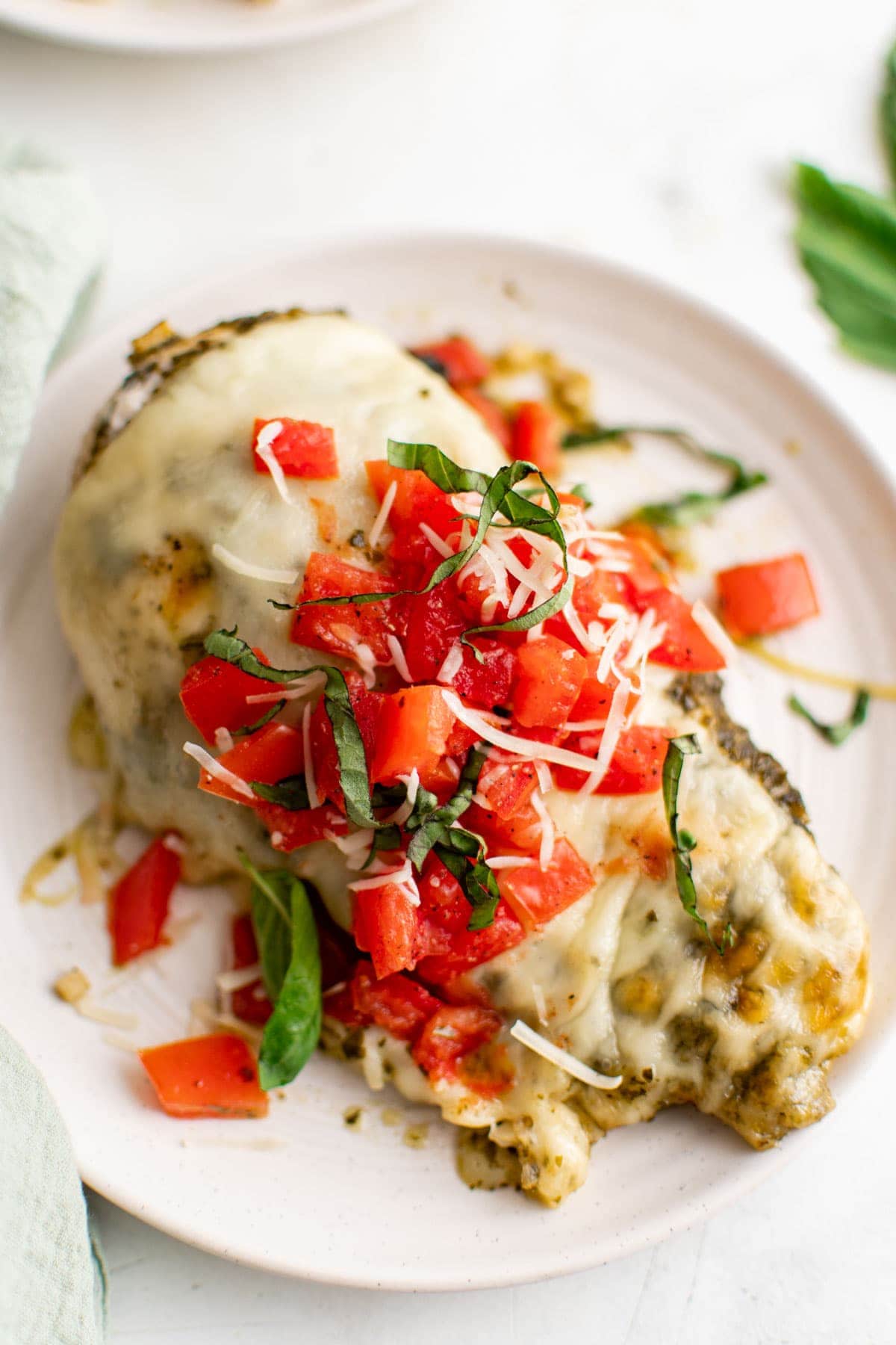 a pesto baked chicken breast on a white plate